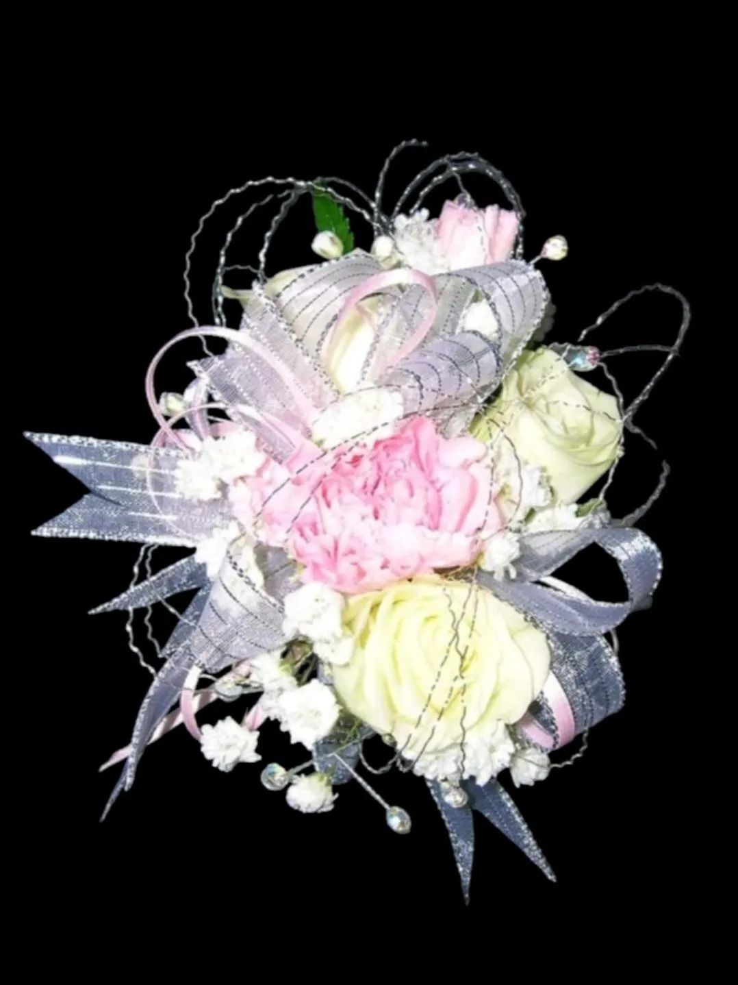Pink, white, and yellow flower corsage with silver ribbon and wire accents against a black background.