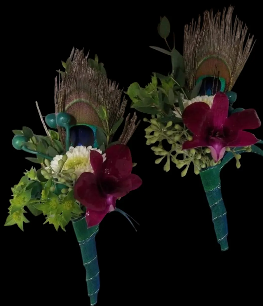 Two boutonnieres with peacock feathers, deep red orchids, and green accents on a black background.