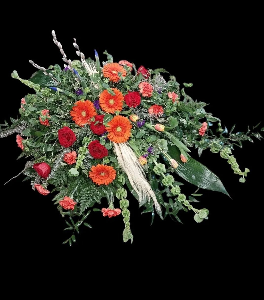 Floral arrangement of orange gerbera daisies and red roses on a black background.