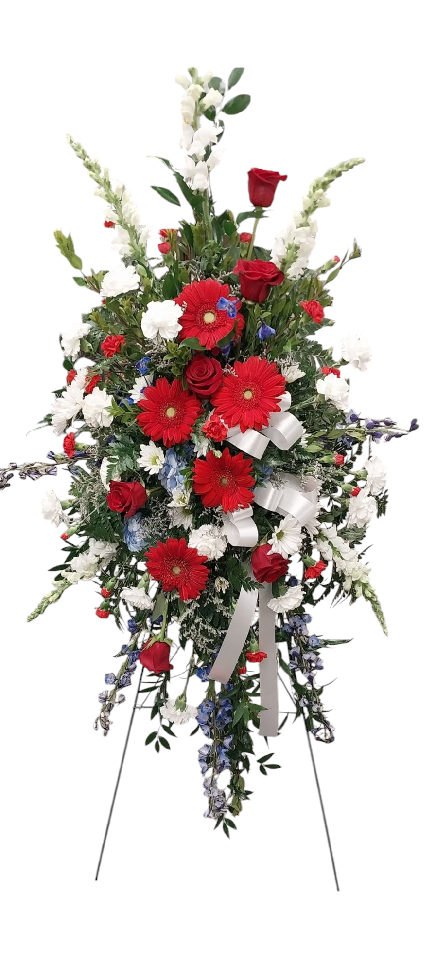A patriotic floral arrangement with red, white, and blue flowers on a stand.