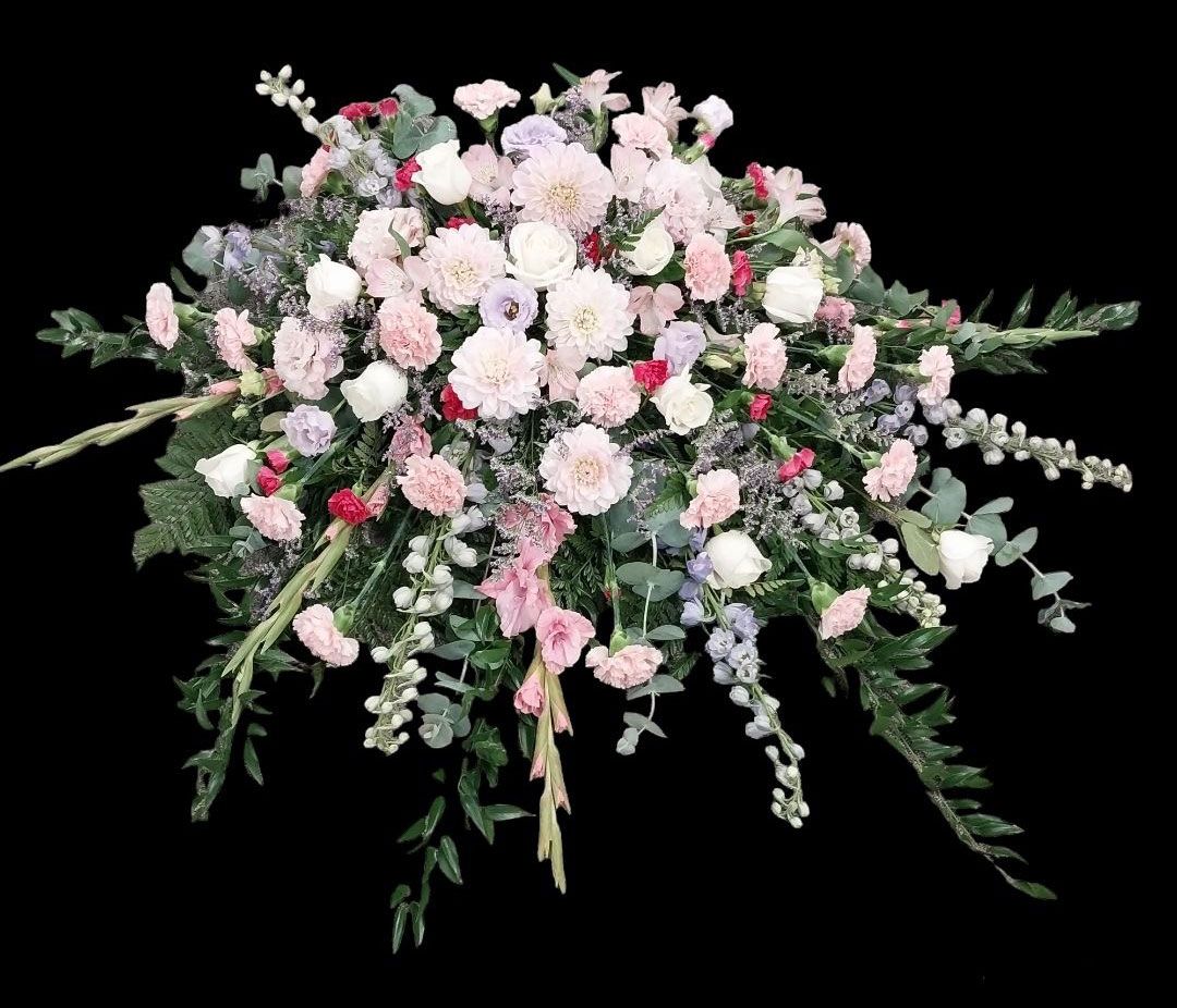 Floral arrangement of pink, white, and red flowers with green foliage, against a black backdrop.