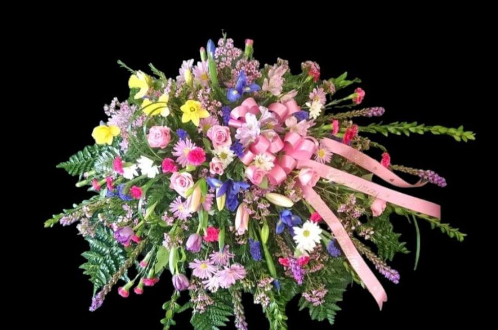 Colorful floral arrangement with pink ribbon against a black background.