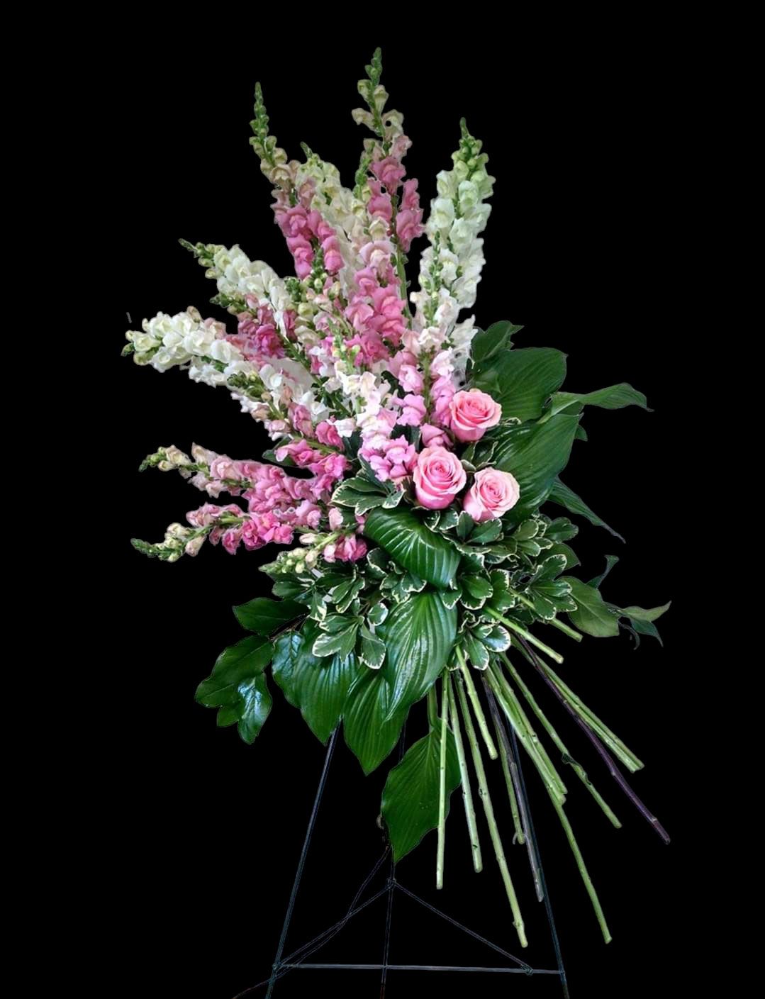 Floral arrangement with pink and white flowers on a black easel.