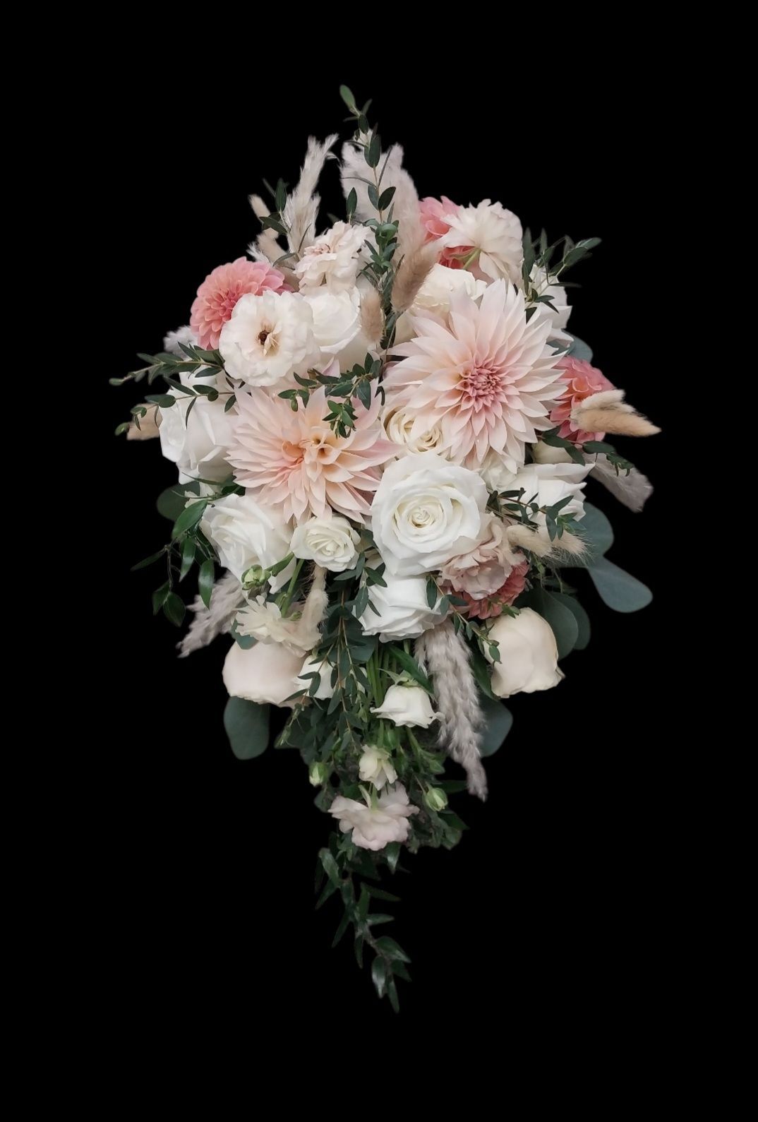 Cascading bridal bouquet with blush dahlias, white roses, and greenery on black background.