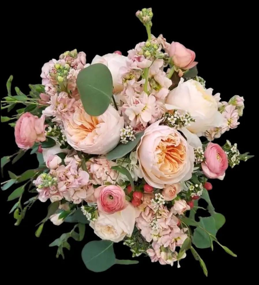 Bouquet of pink and peach flowers with green foliage, against a black background.
