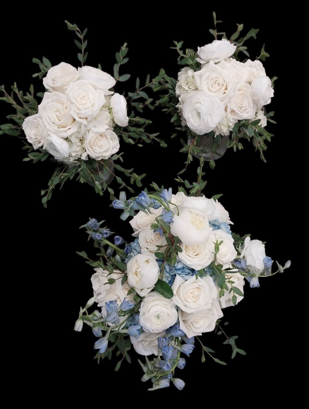 Three bouquets of white roses and green foliage; one with blue flowers.