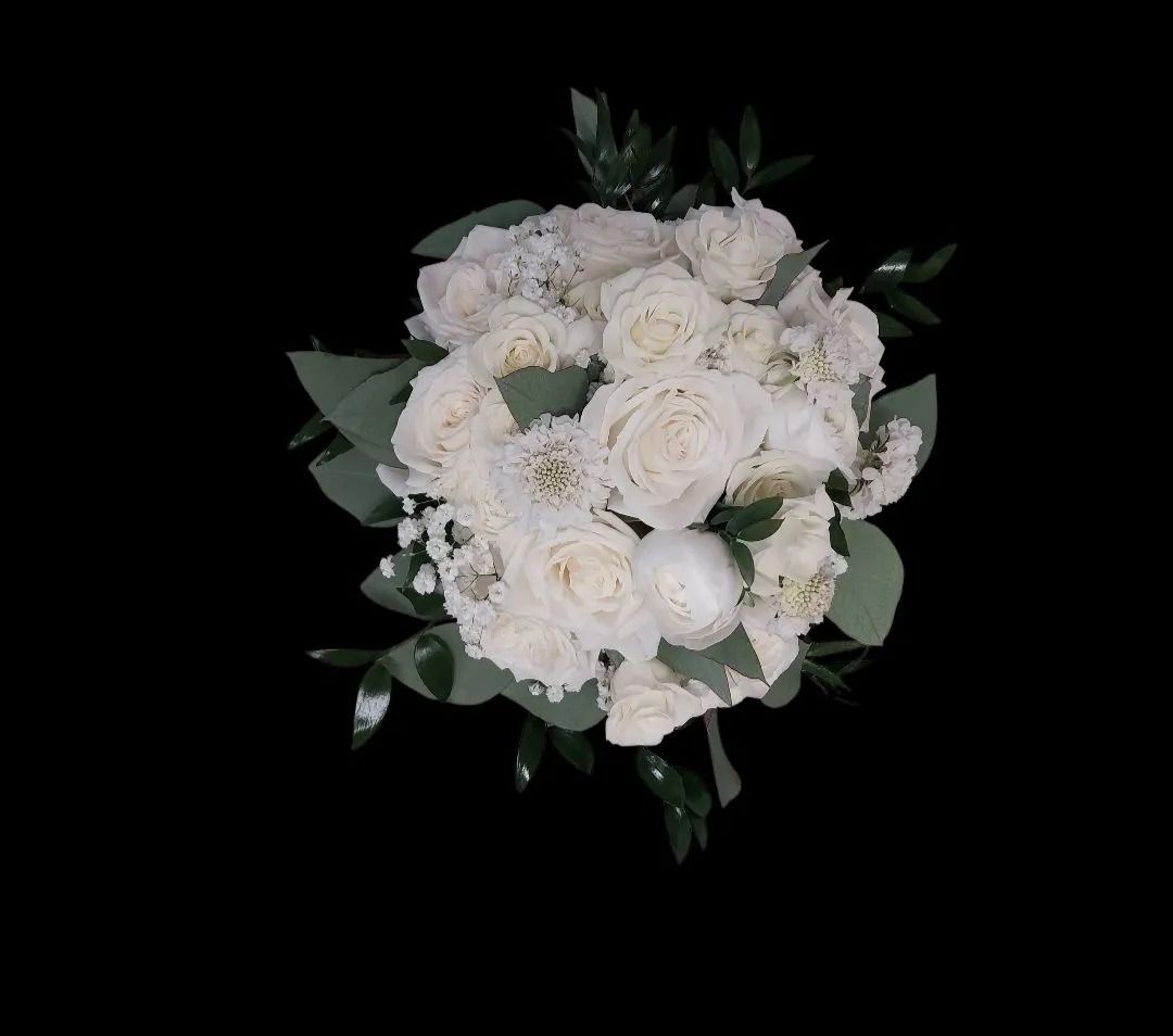 White flower bouquet with greenery against a black background.