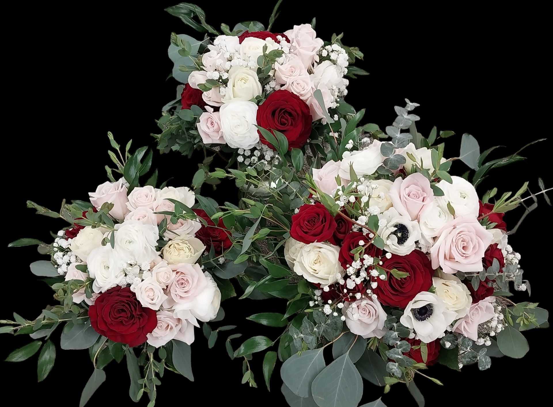 Three wedding bouquets with red, white, and pink roses and greenery on a black background.