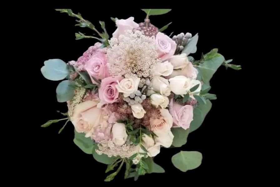 Bouquet of light pink and white roses, hydrangea, and greenery on black background.