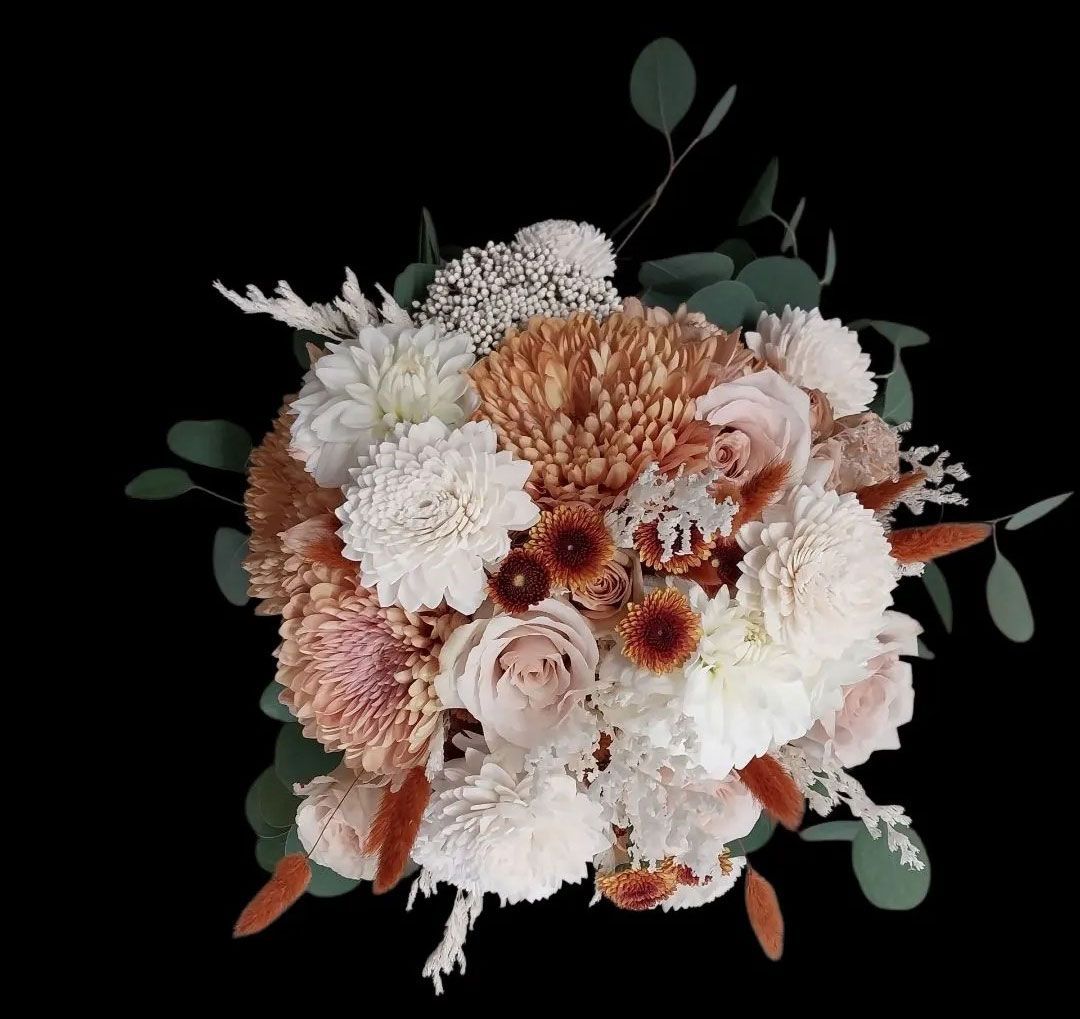 Bouquet of white, peach, and brown flowers with green eucalyptus leaves against a black background.