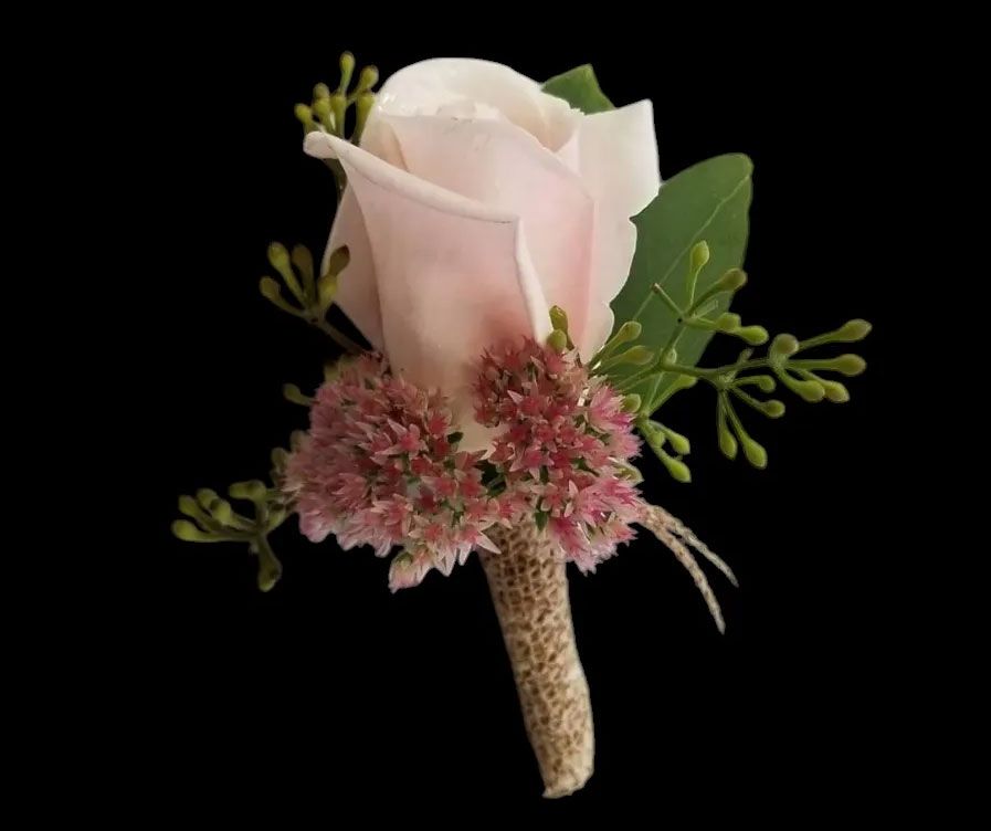 Pink rose and greenery boutonniere, wrapped stem, against a black background.
