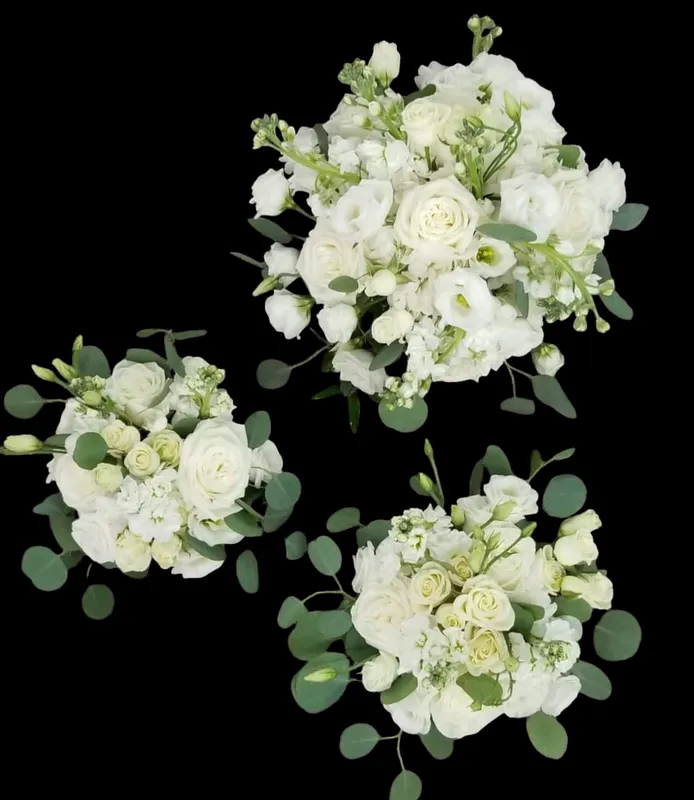 Three white floral bouquets with green foliage on a black background.