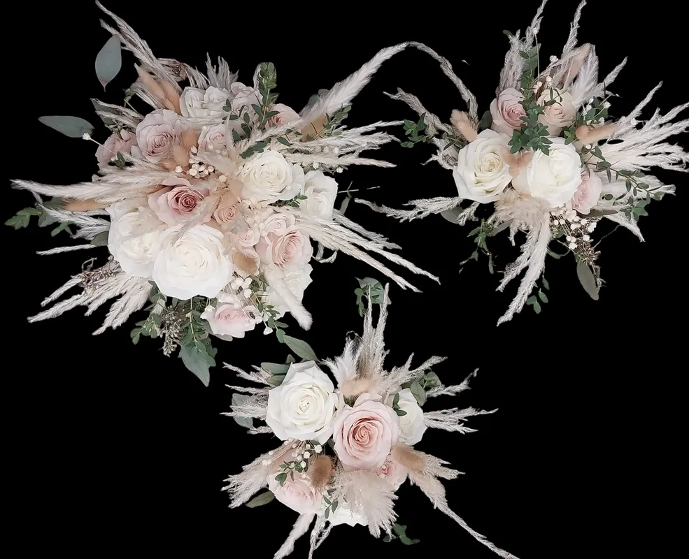 Three bouquets of white and pink roses with fluffy, cream-colored plumes and greenery against a black background.