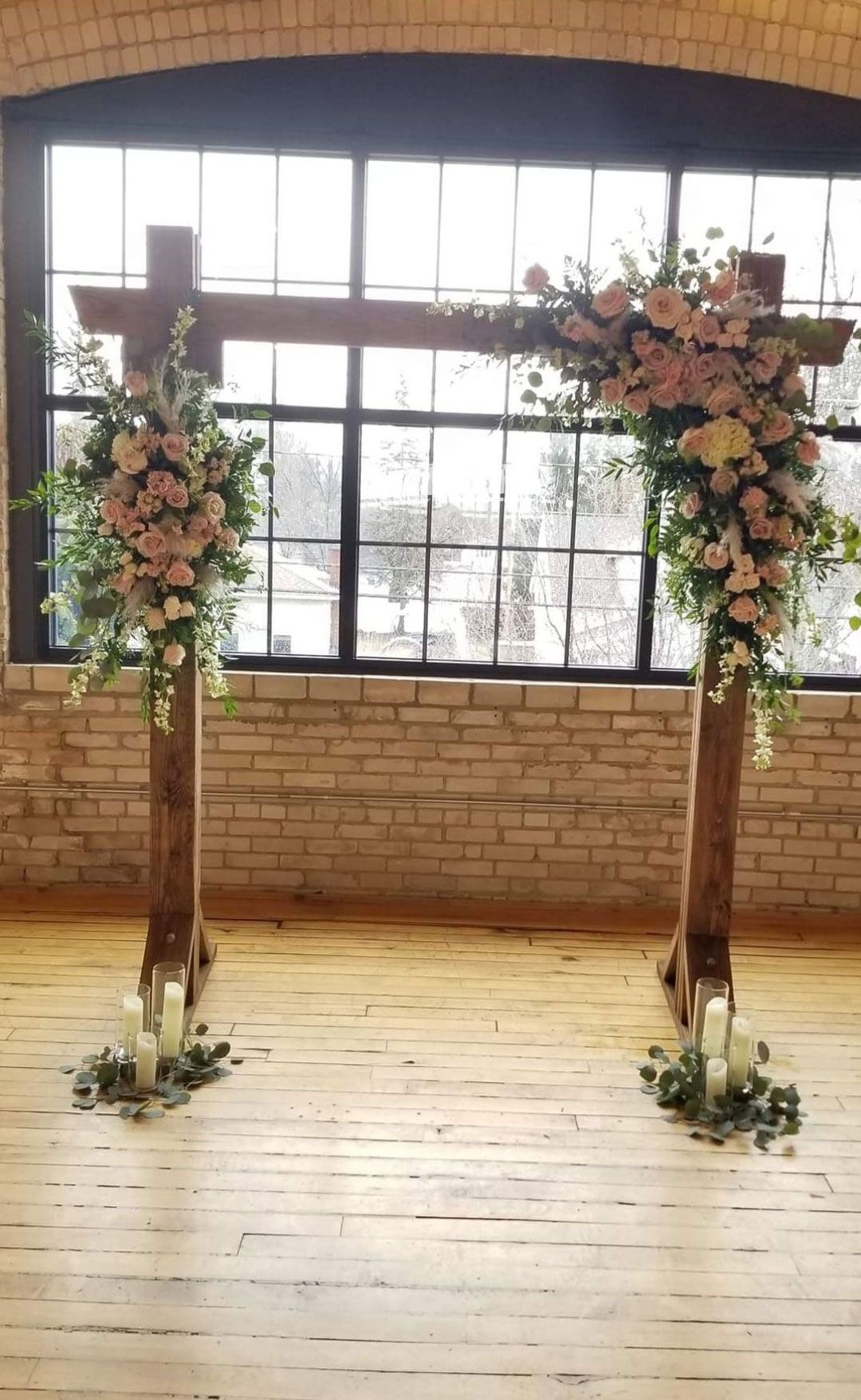 Wedding arch with floral arrangements in front of a window.