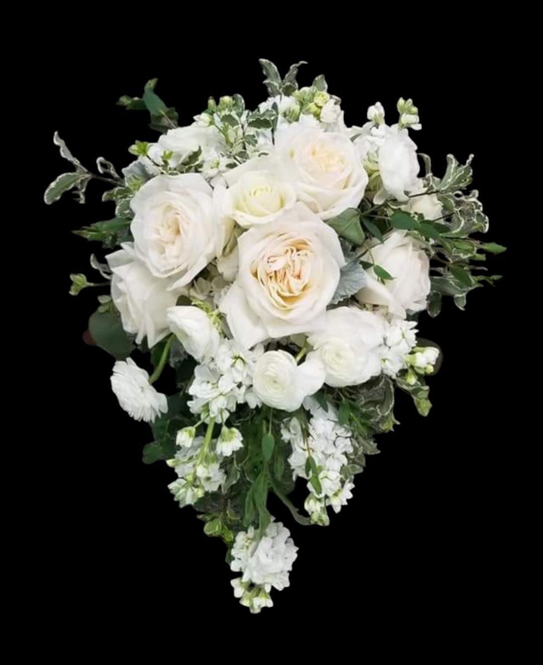 White bridal bouquet with roses, ranunculus, and stock flowers. Green foliage.