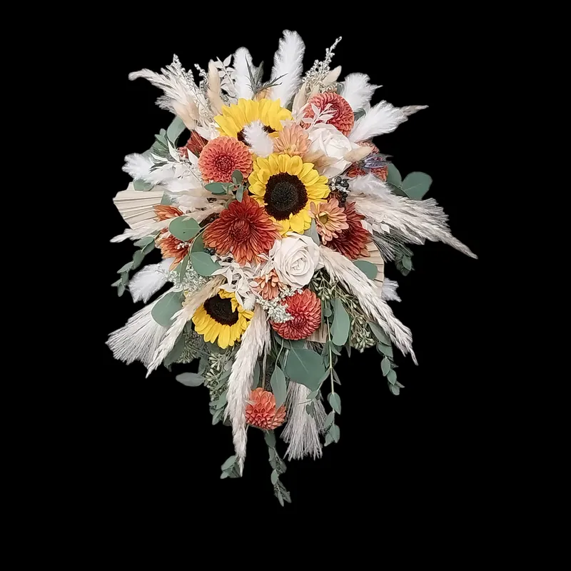 Cascading bridal bouquet: sunflowers, orange blooms, pampas grass, eucalyptus, against black background.