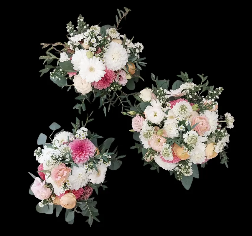 Three bouquets of white, pink, and peach flowers arranged with greenery against a black background.