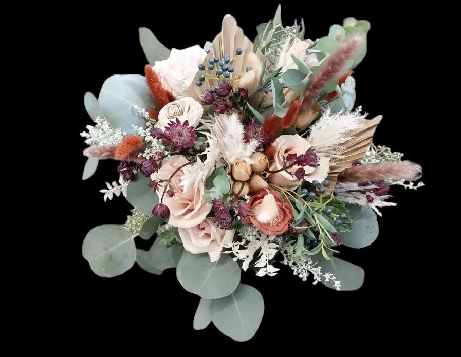 Bouquet of soft pink and brown flowers with green eucalyptus leaves on a black background.