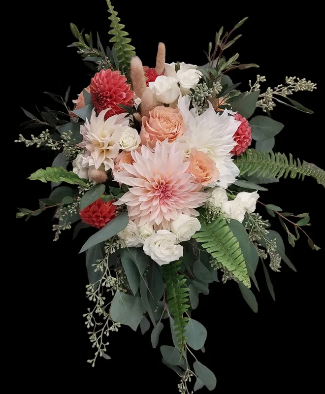 Cascading bouquet with coral dahlias, white roses, peach blooms, and greenery.