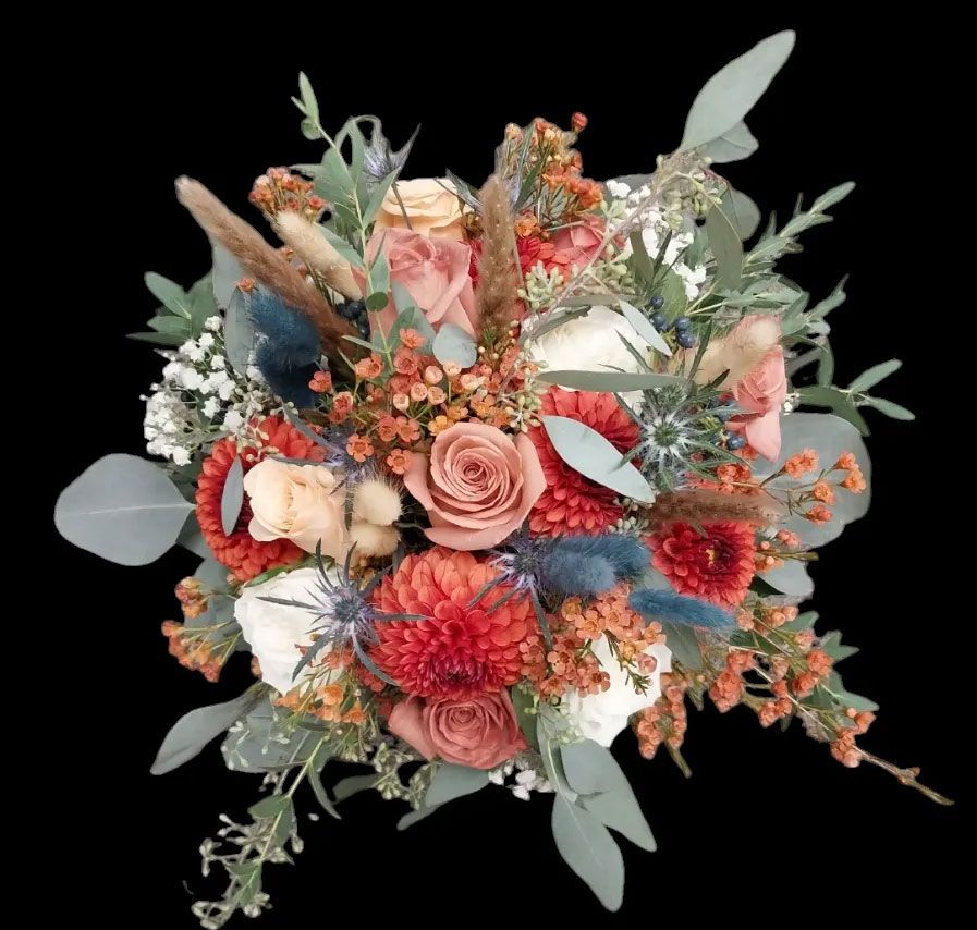 Bouquet of autumn-toned flowers, including roses, dahlias, and eucalyptus, on a black background.