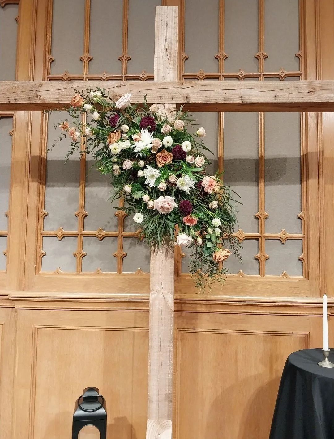 Wooden cross decorated with flowers in a church setting.