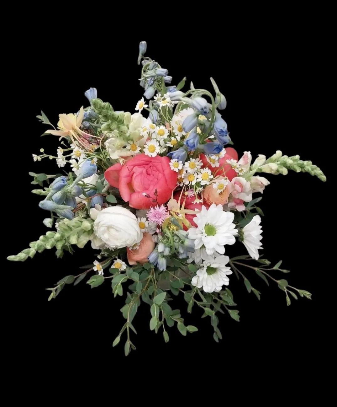 Bouquet of colorful spring flowers, including pink peony, white daisies, and blue delphinium.