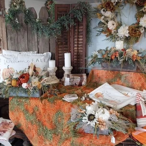 Autumn display with pumpkins, wreaths, candles, and fall decor.