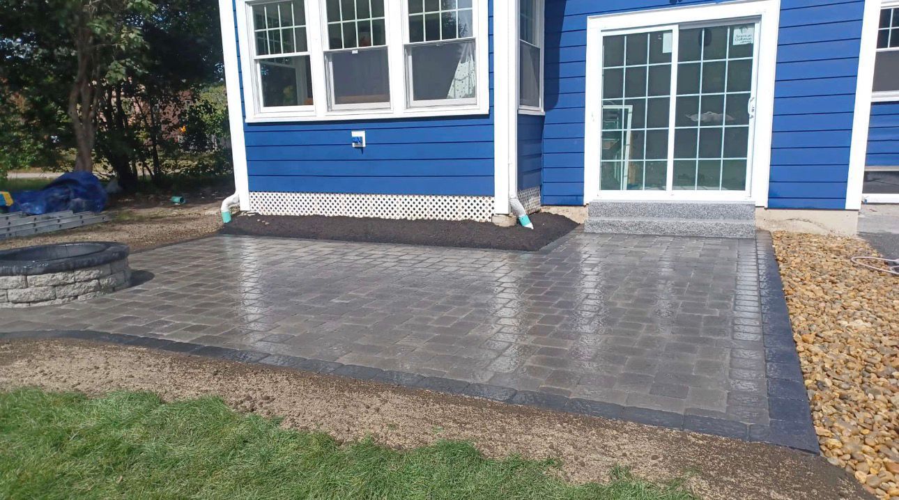 Blue house with patio, fire pit, and gravel border.