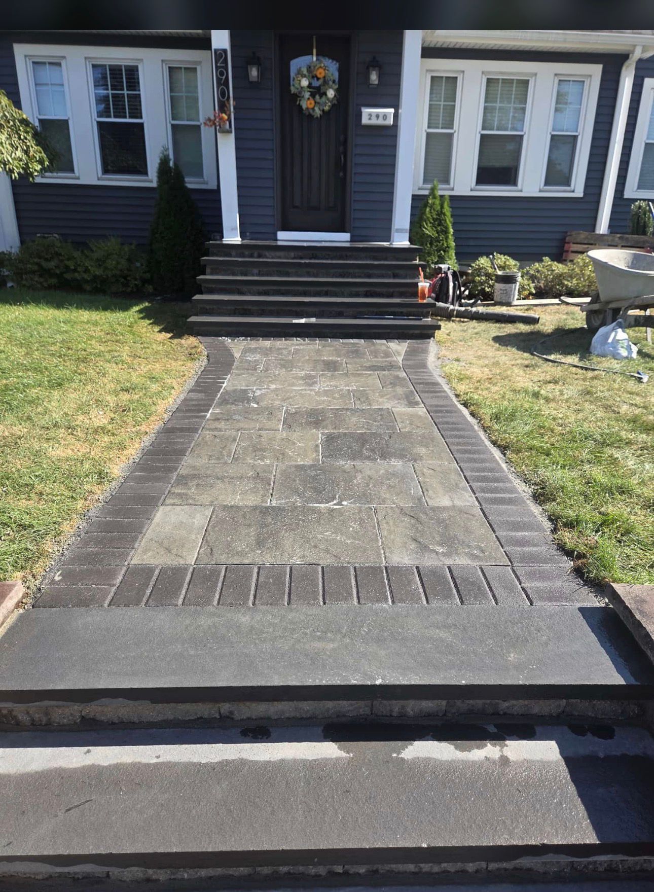 Brick walkway and steps leading to a dark blue house with white trim.