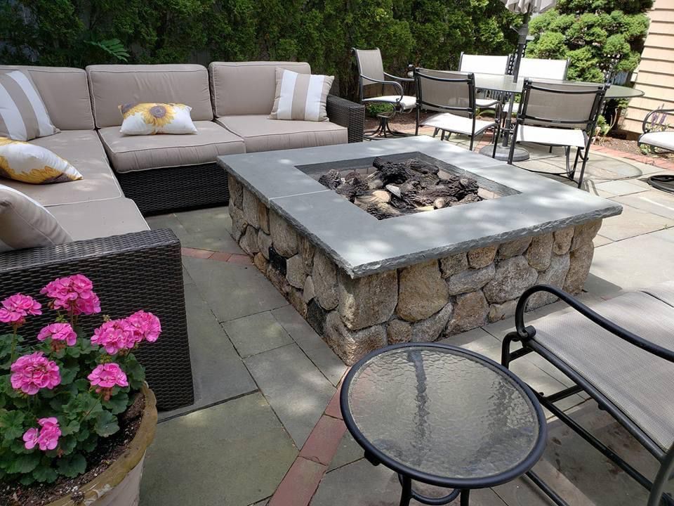 Outdoor patio with stone fire pit, sectional sofa, and seating.