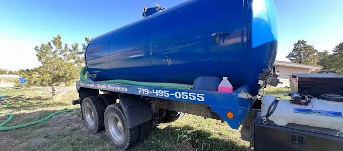 Blue water tanker truck parked on a trailer hitch in a sunny outdoor yard