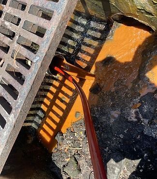 A manhole cover with a hose coming out of it.