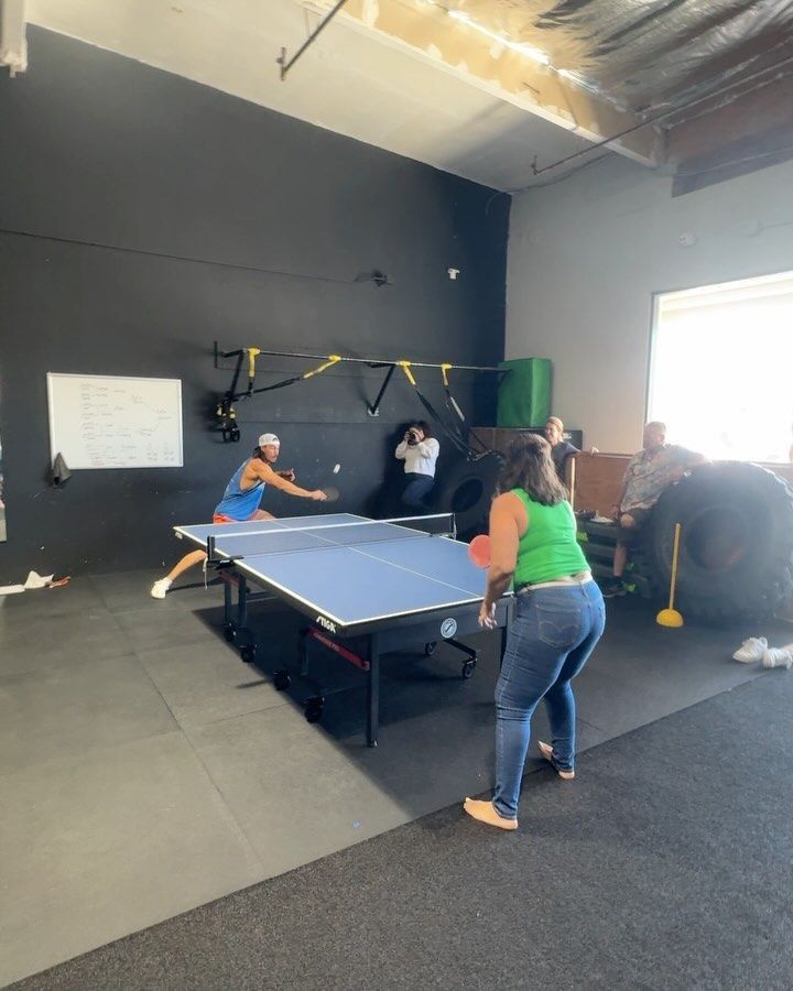 A group of people are playing ping pong in a gym.
