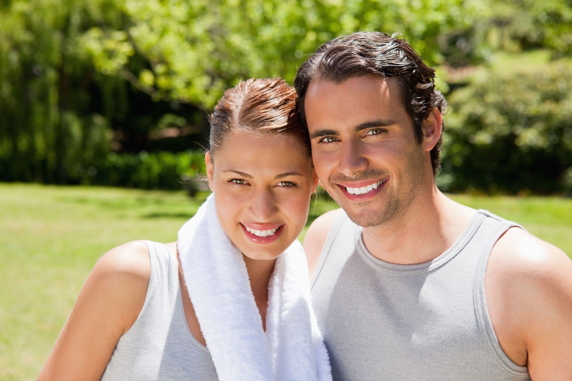 A smiling person lying prone on a white towel during a massage session.