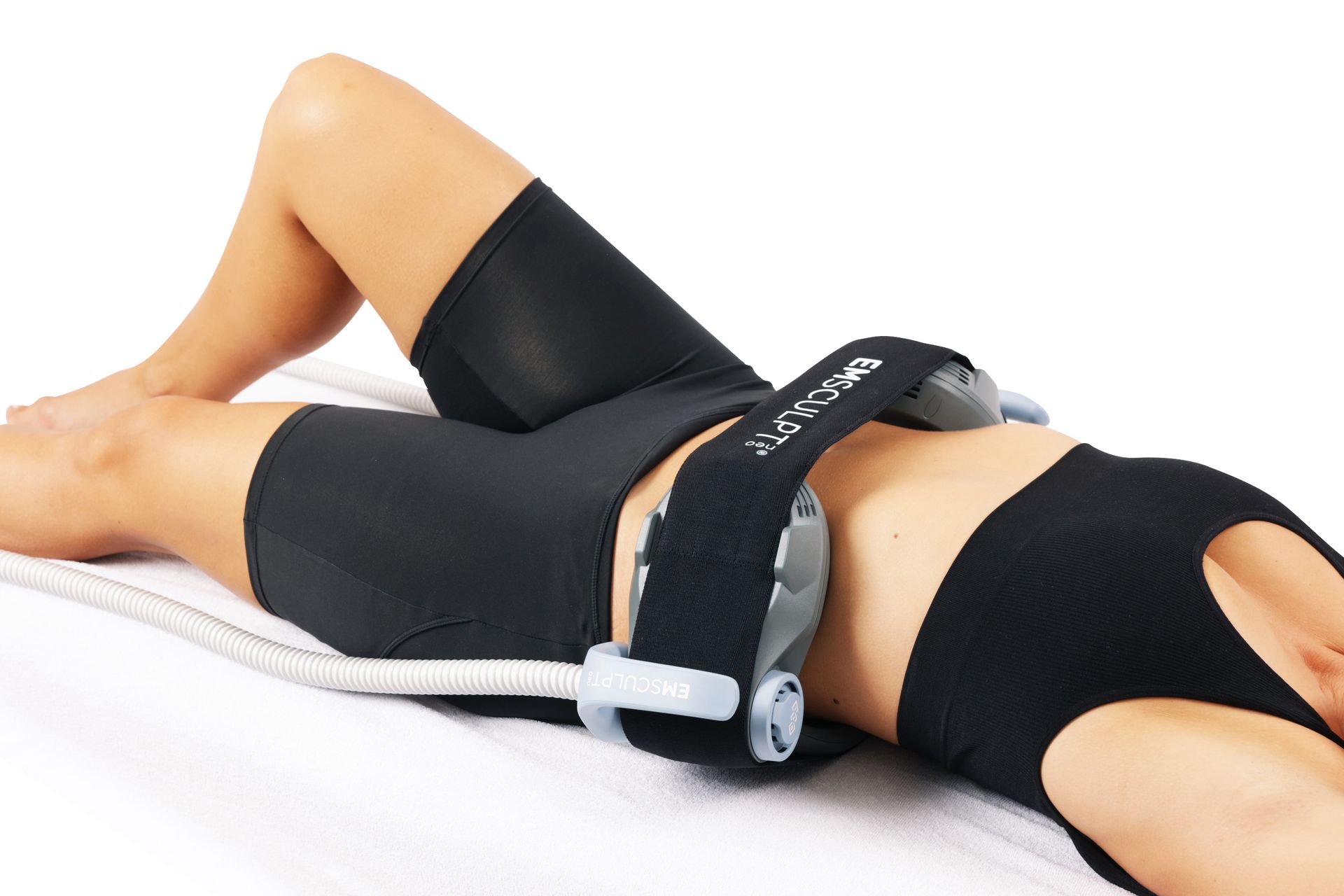 A person lying down wears a black compression belt with grey support attachments around their waist.