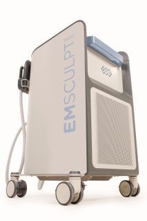 A white and grey Emsculpt body contouring medical device on wheels, viewed from a low angle against a white background.