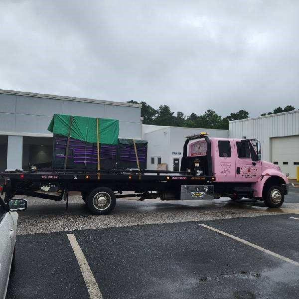 A pink tow truck is parked in a parking lot.