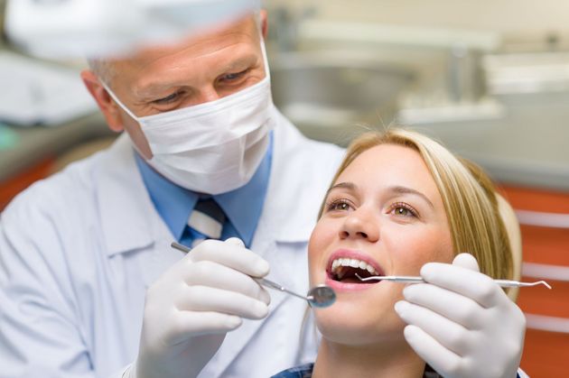 Dentist examining a patient’s teeth with a dental mirror in a bright clinic
