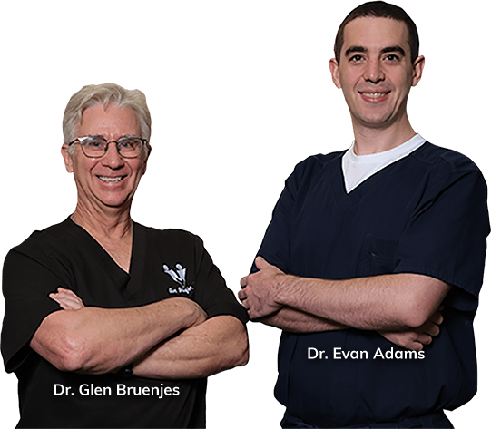 Two medical professionals in scrubs standing with arms crossed, labeled Dr. Glen Bruenjies and Dr. Evan Adams.