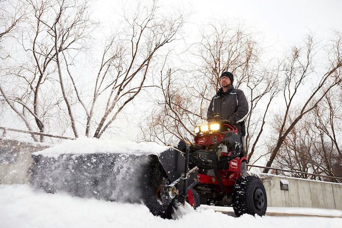 Man using a red snowblower, clearing snow outdoors