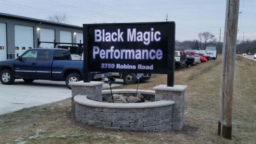 Black Magic Performance sign at 2750 Robens Road in front of a brick wall and vehicles on the side of the road