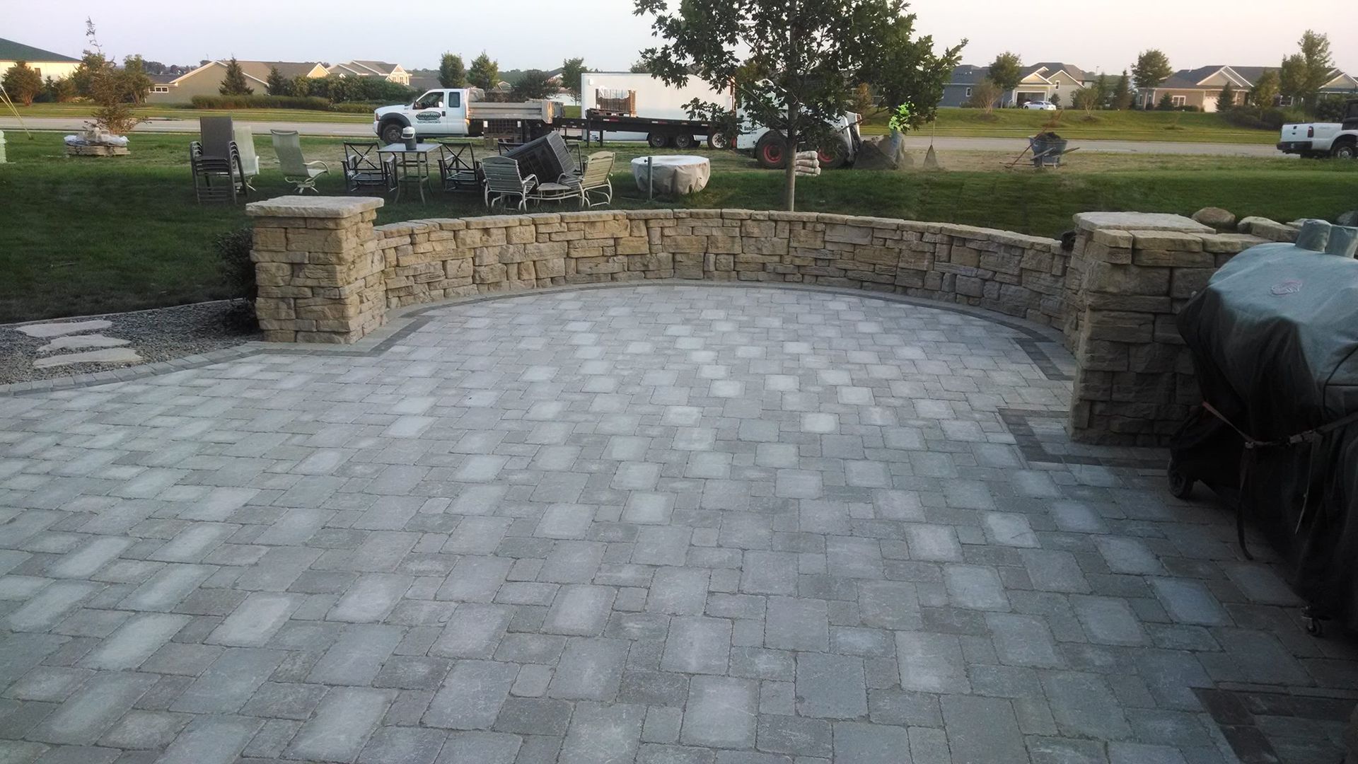 Stone patio with curved stone wall, pavers, and landscaping in an outdoor setting