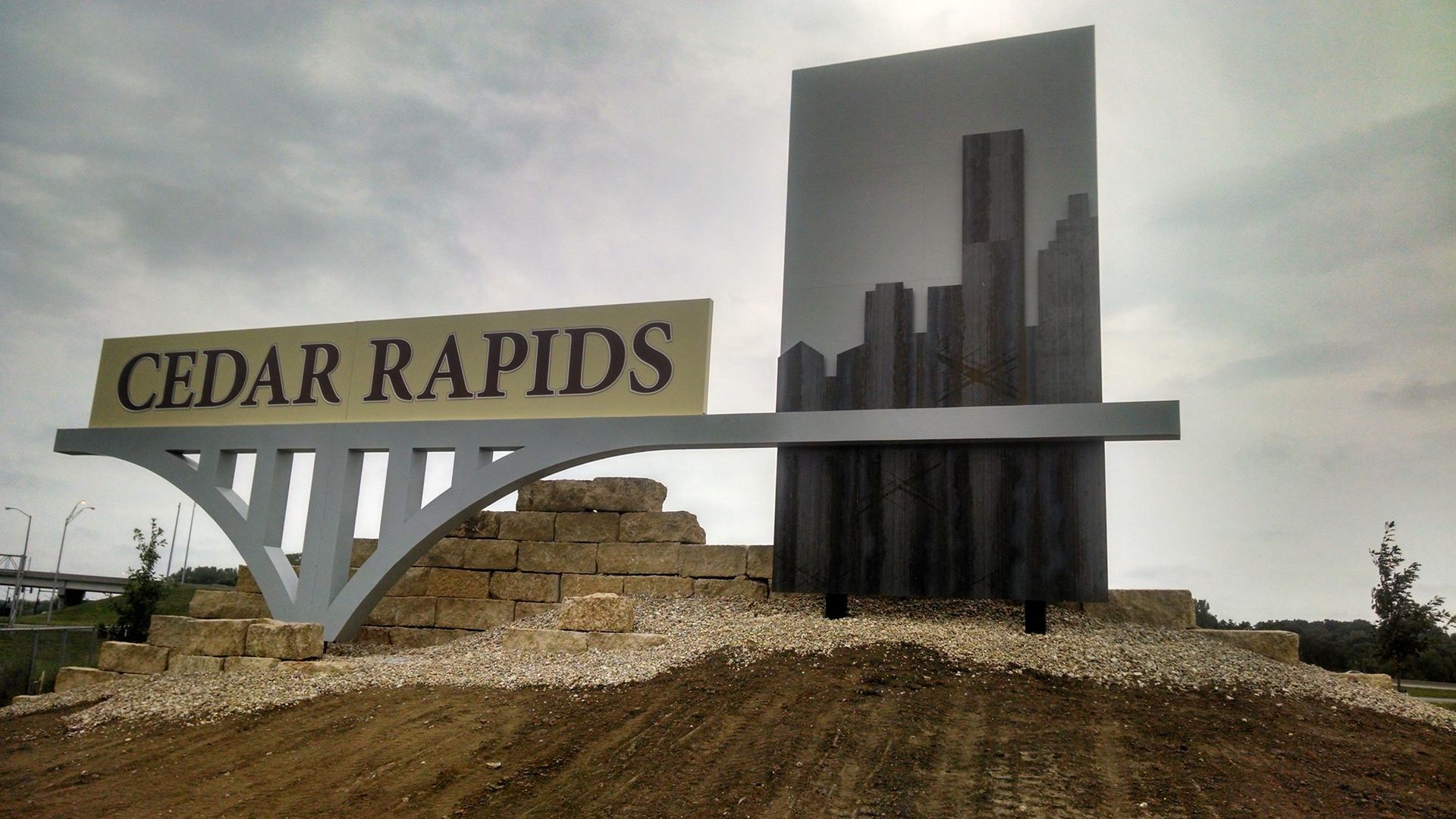 Sign for Cedar Rapids with stylized cityscape and arched support