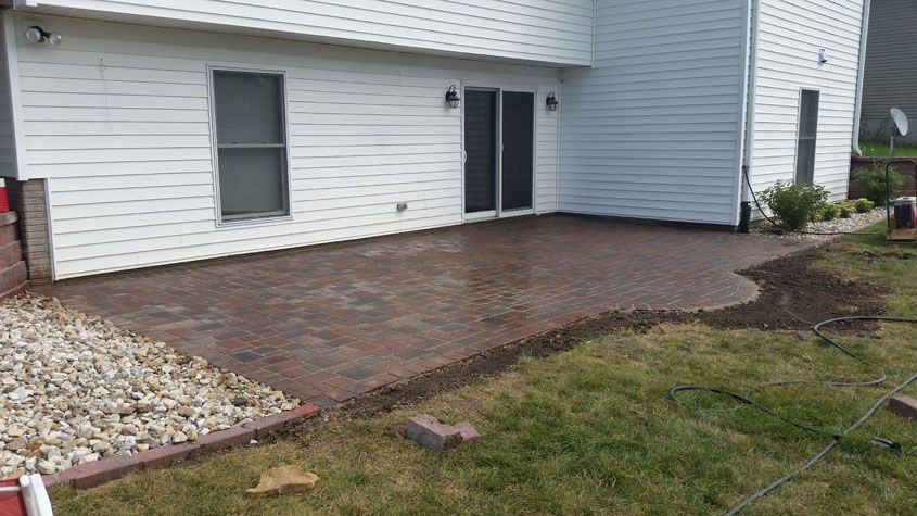 Brick patio outside a white house with a sliding door and window