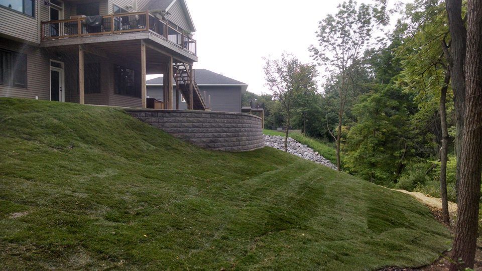 Green grassy hillside with a house and retaining wall