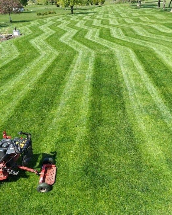 A large, well-manicured green lawn with a zigzag mowing pattern