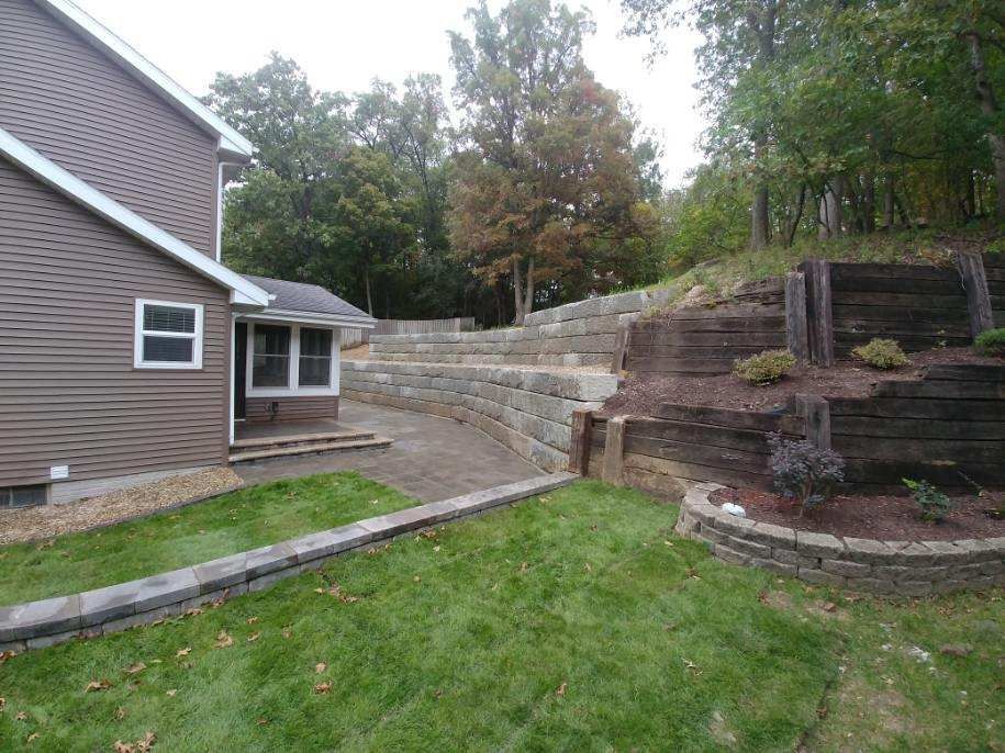 Backyard with house, retaining walls, lawn, and trees