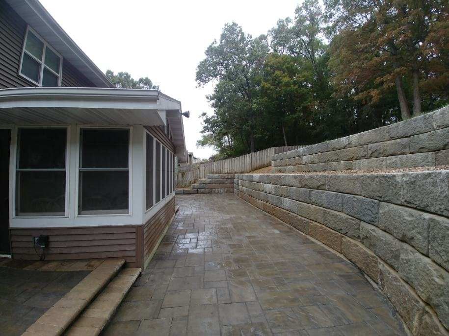 Exterior view of a house with a concrete patio and a tiered retaining wall
