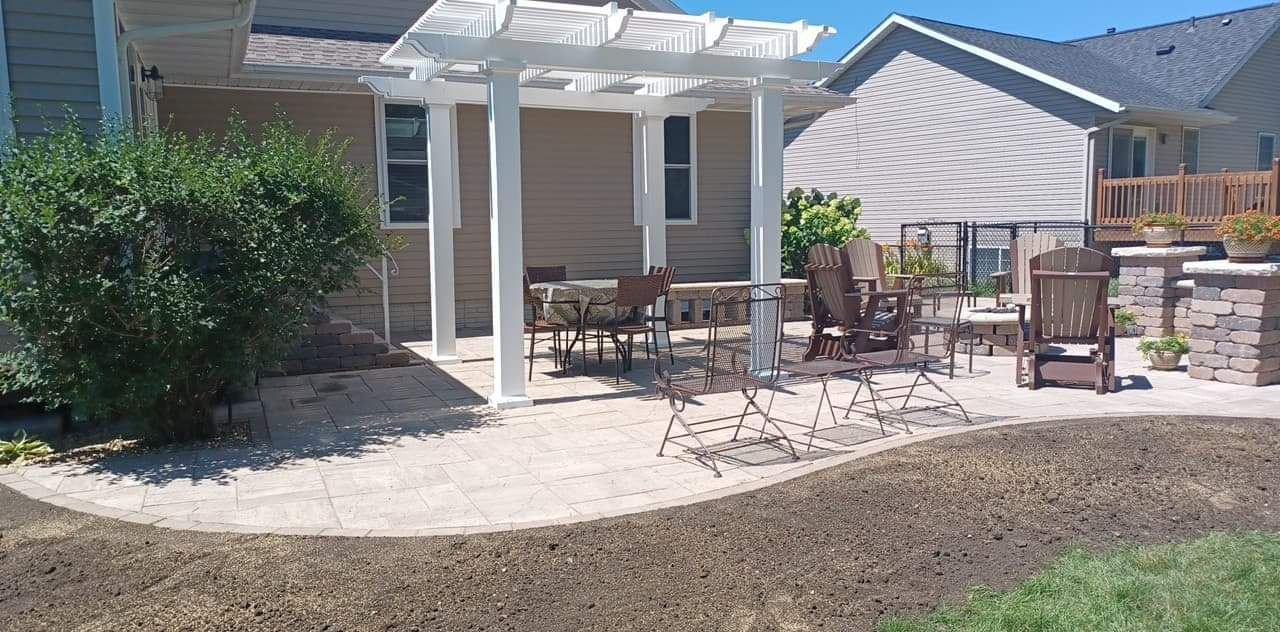 Backyard patio with a white pergola, seating, and landscaping.