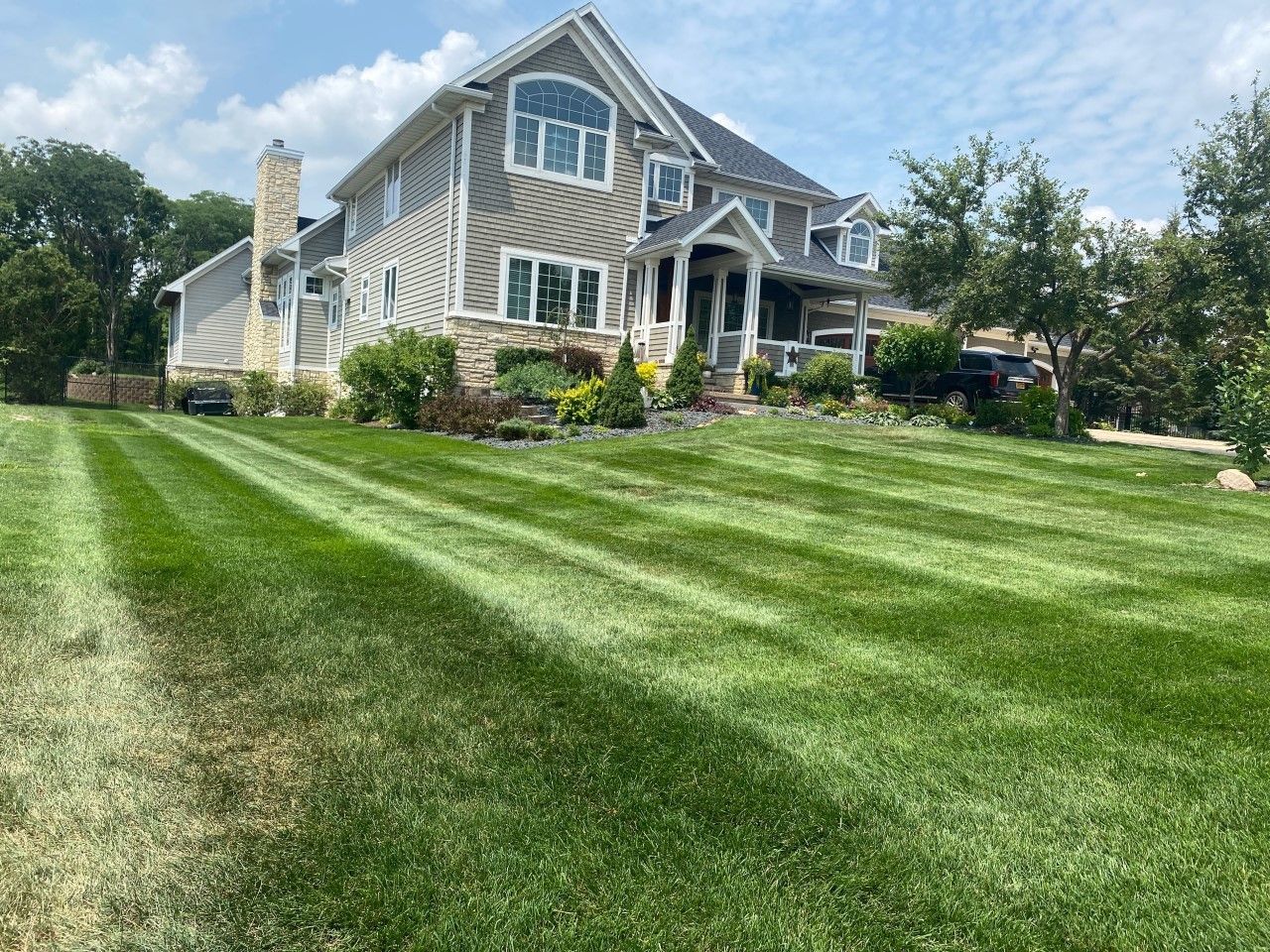 Two-story house with striped, green lawn